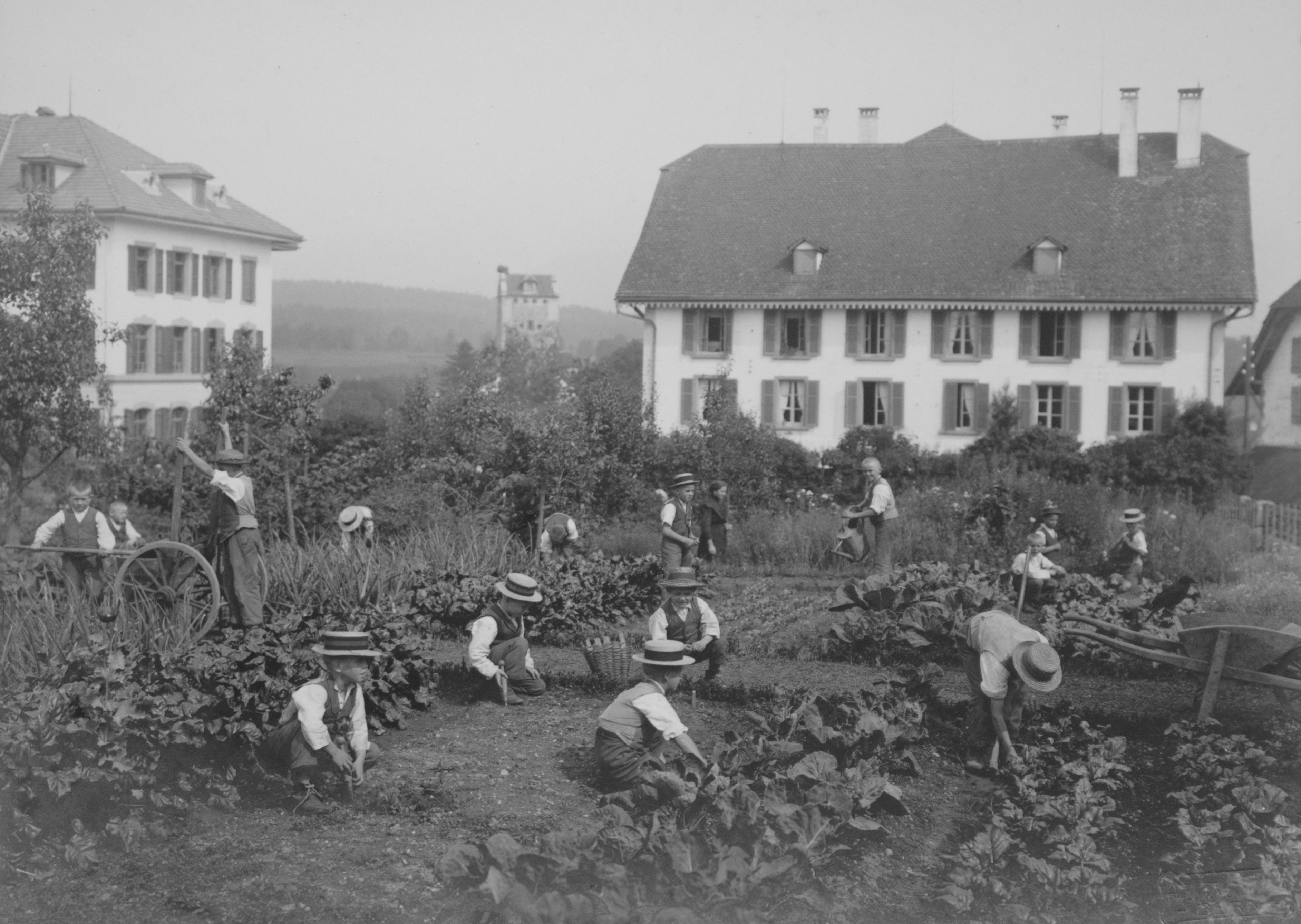 Vue extérieure d'une institution pour enfants à Berne de 1914, où les enfants travaillent dans le jardin devant la résidence.